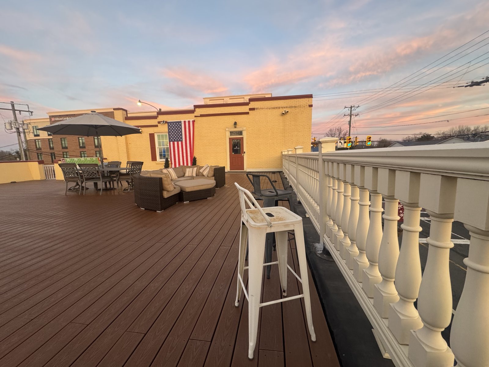 The Hive's rooftop deck at sunset with lounge seating, a dining table and the American flag