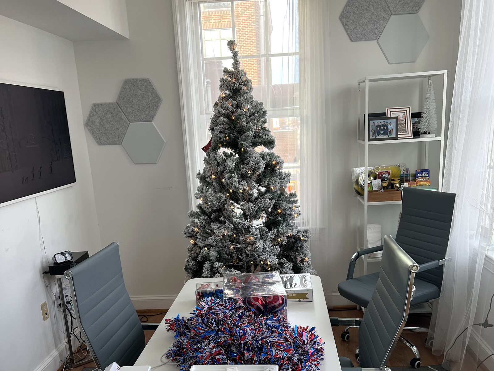 A flocked holiday tree with lights in a bright Hive meeting room, garland on the table