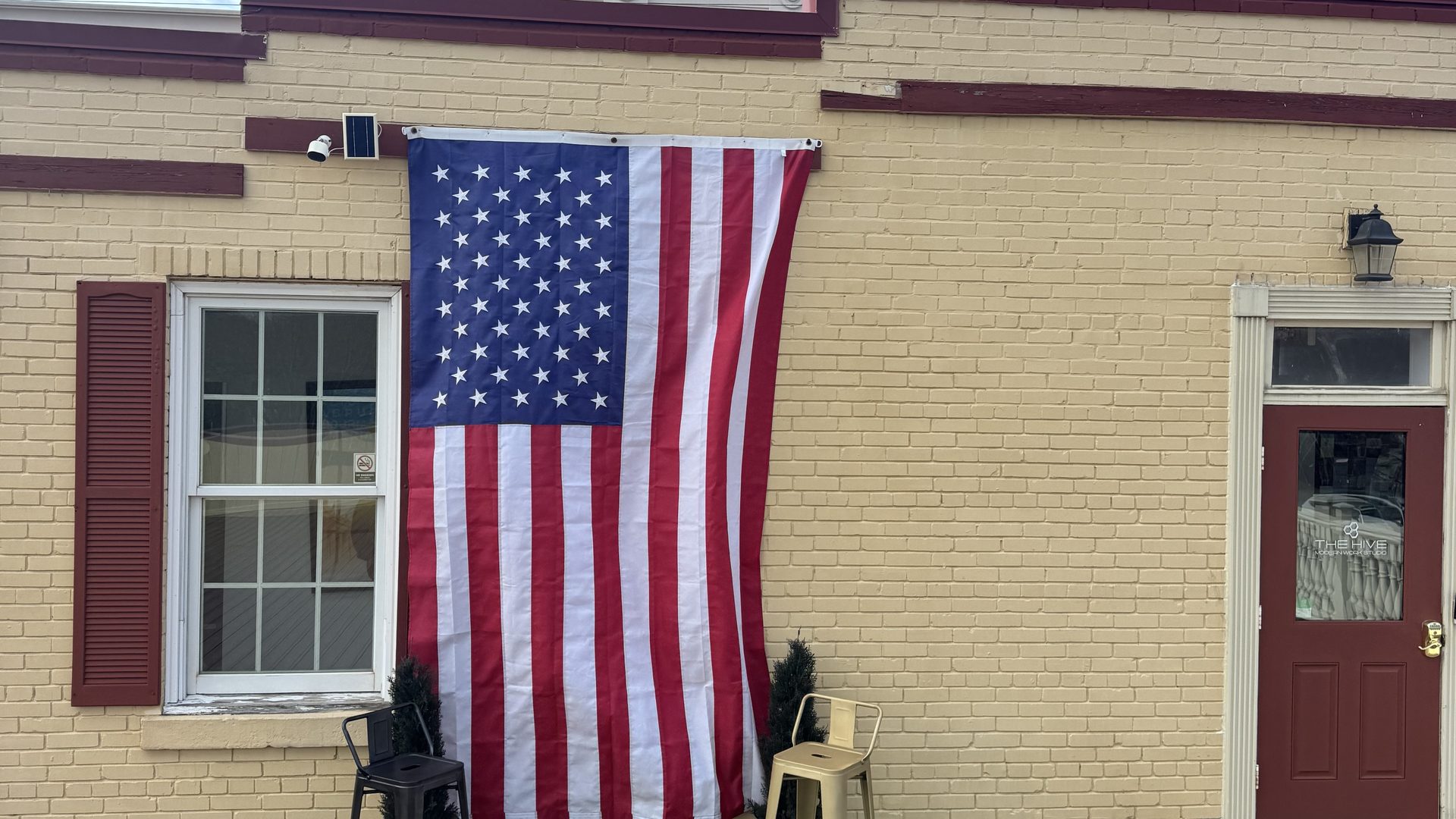 The Hive's Haymarket storefront with a large American flag and red entry door