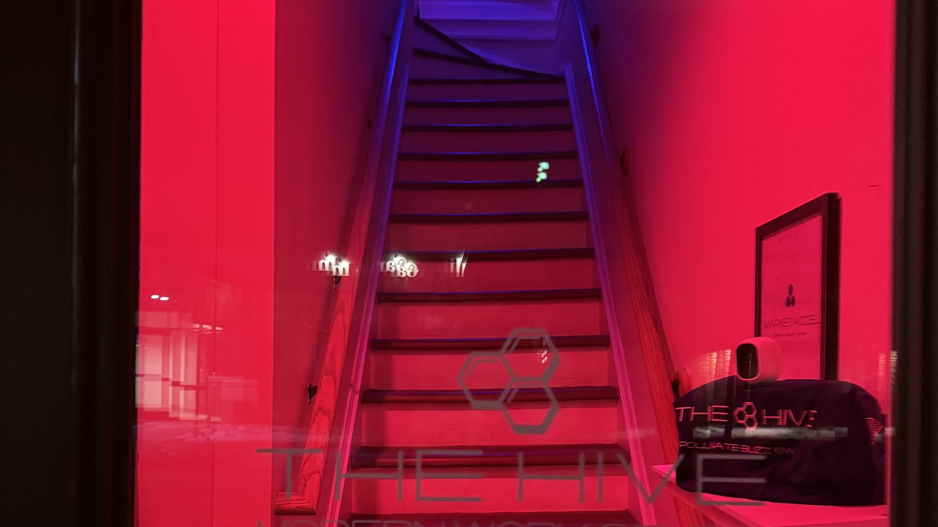 The Hive's signature red-lit staircase entry with the etched glass logo