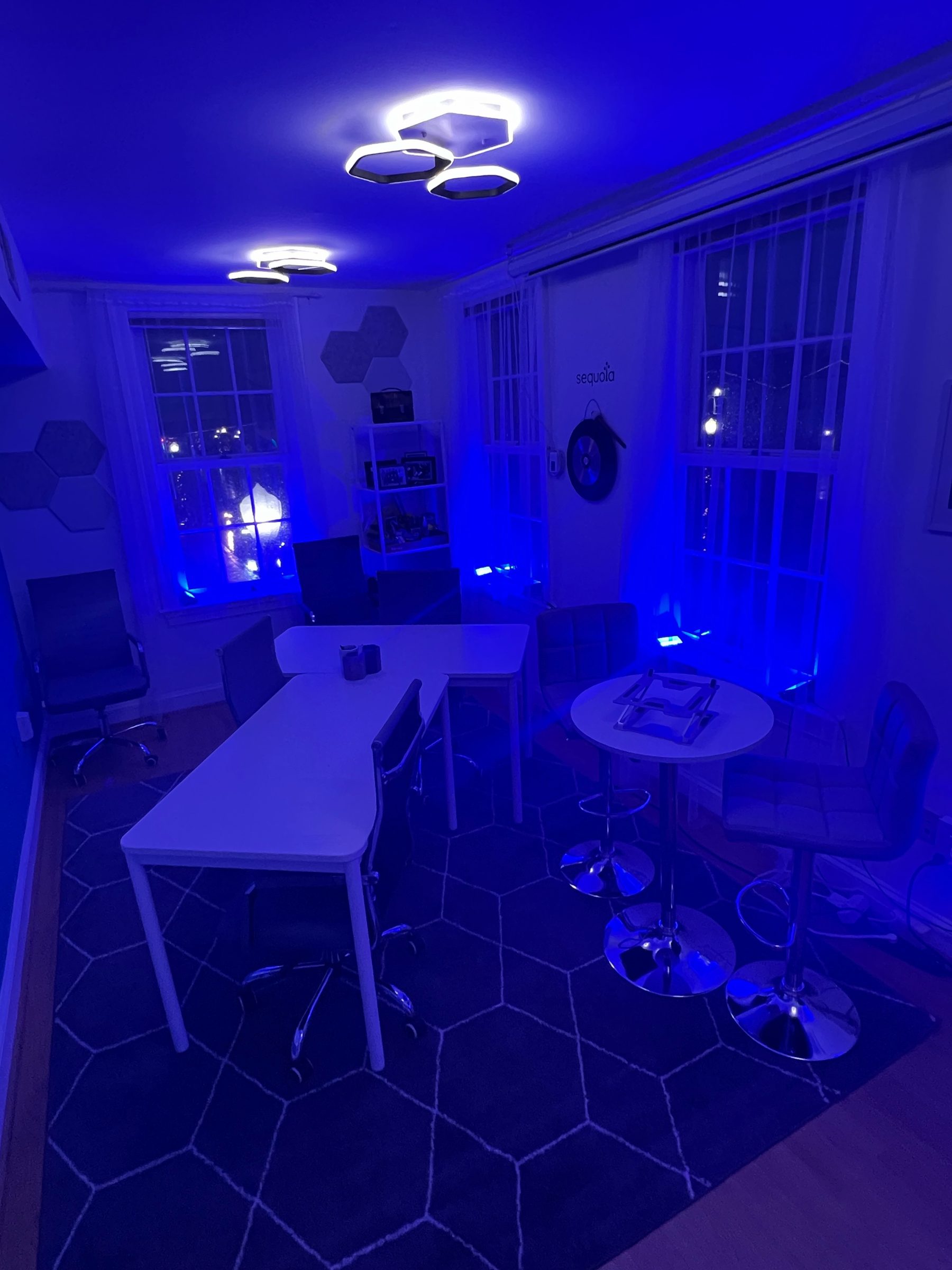 A room at The Hive washed in deep blue ambient lighting with a styled table and hexagon patterned floor