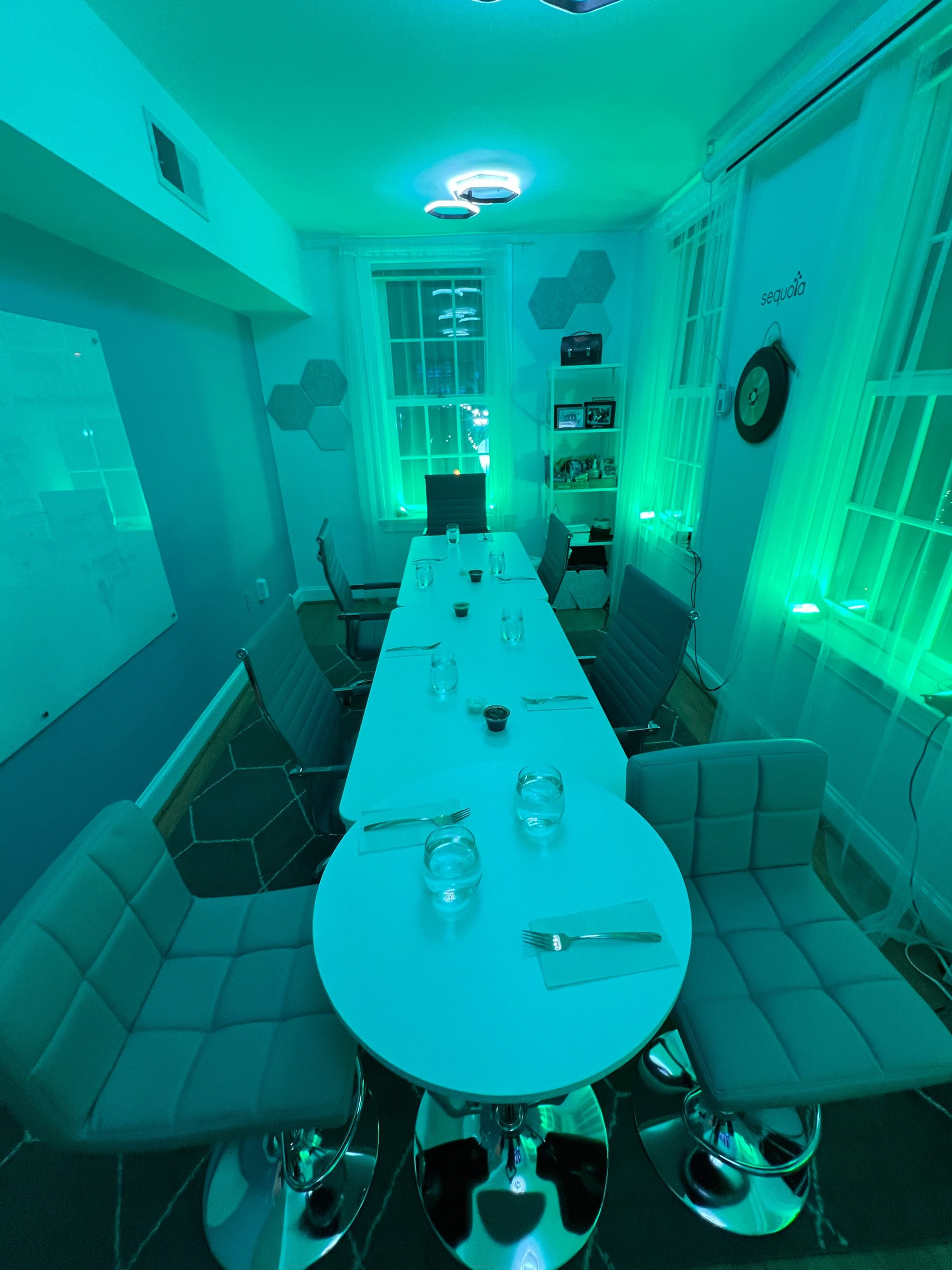A long executive dinner table at The Hive dressed in white with place settings under dramatic teal ambient lighting
