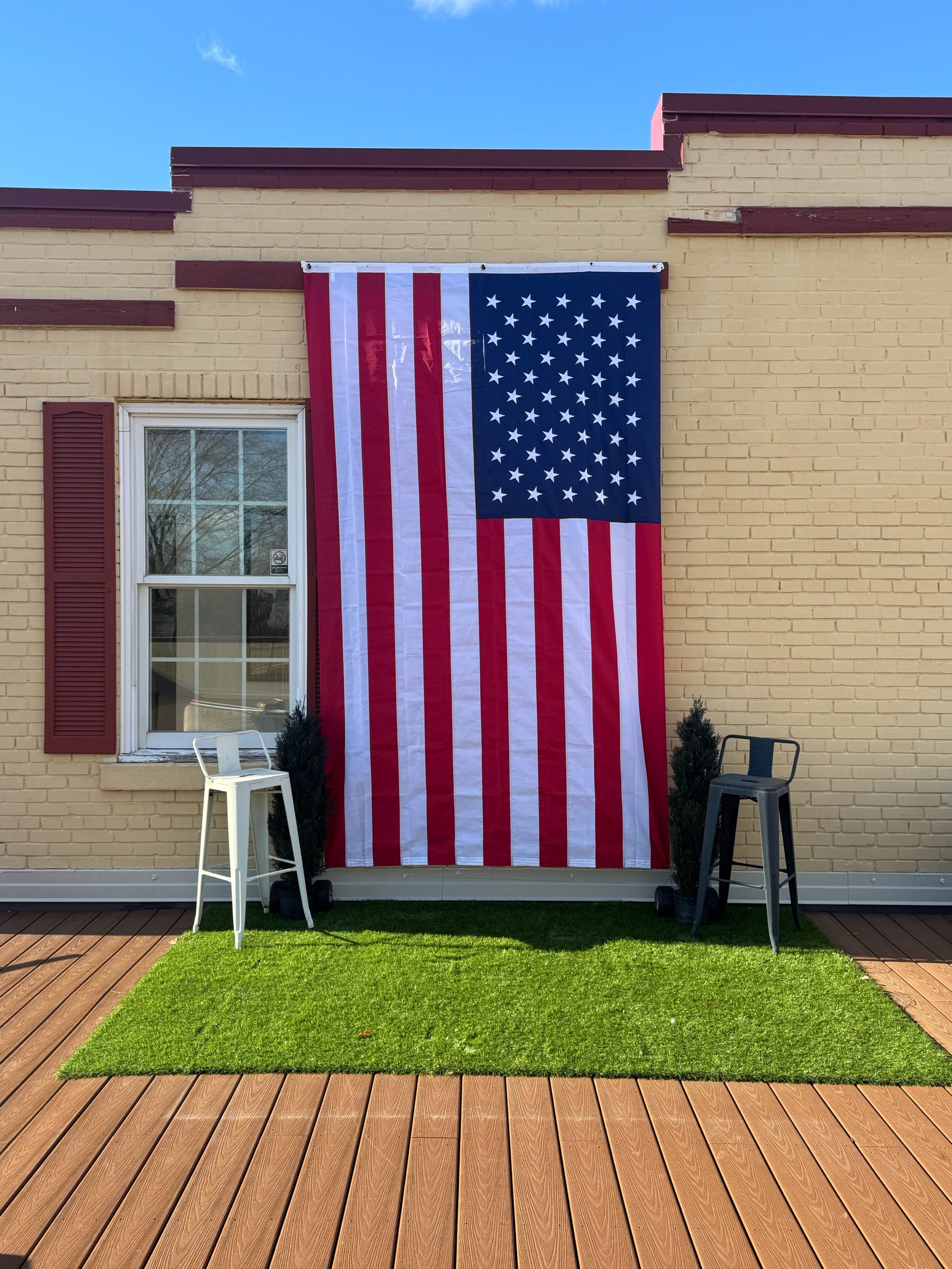 The Hive rooftop styled for a private daytime gathering with a large American flag, turf and cafe seating