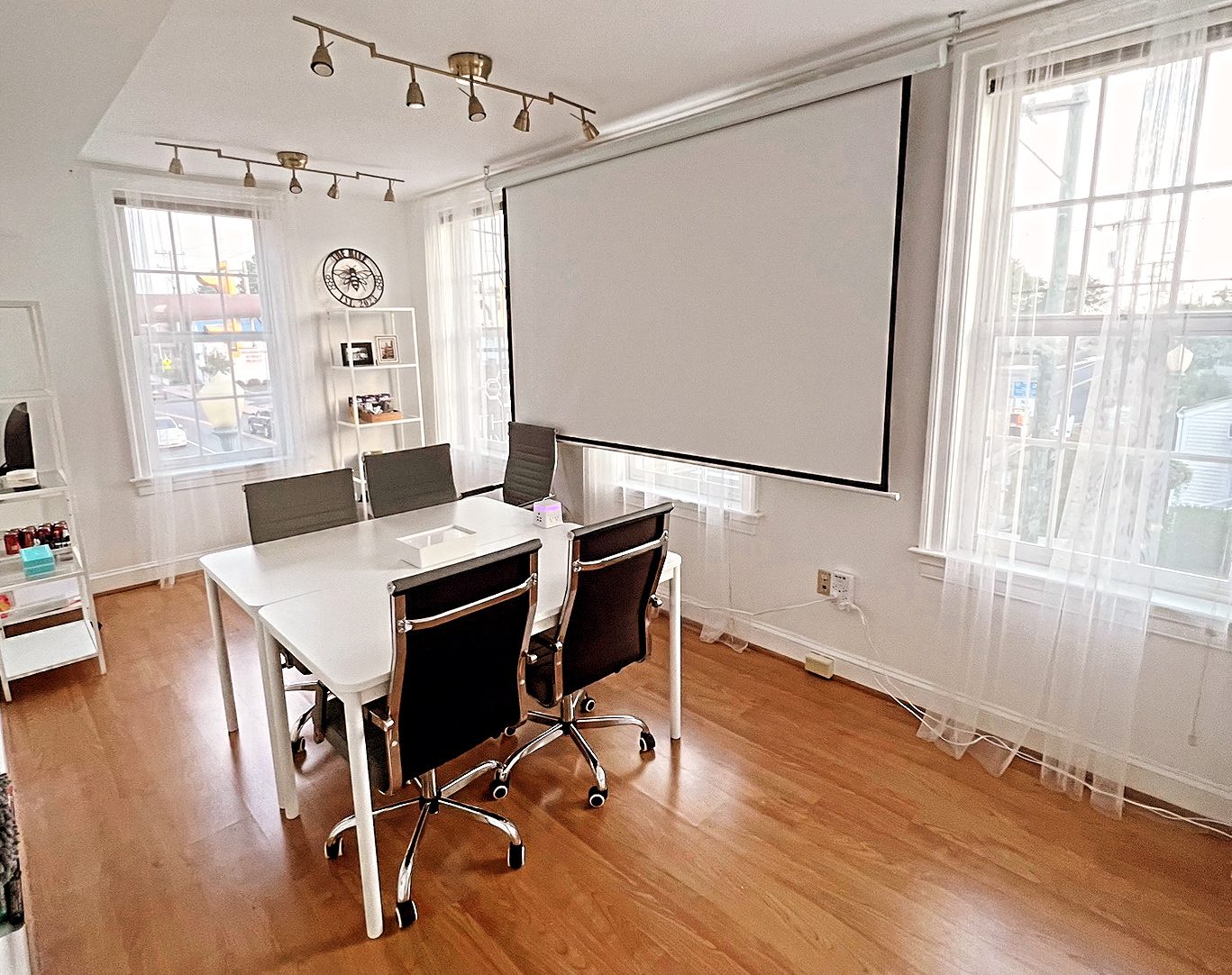 A bright strategy session setup at The Hive with a white conference table, leather chairs and a projection screen
